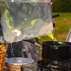 Close up image of the Folding 10L Water Carrier by OLPRO pouring water from the tap in to a camping saucepan.