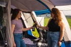 two friends talk & share a drink in the spacious living area of a Cocoon V2 Campervan Awning by OLPRO