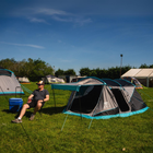 A man is seated in an Olpro camping chair beside a Stafford 3.0 tent at a campsite.