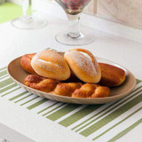 Husk Oval Plate  by OLPRO, pictured on a dining table, displaying bread rolls. Lightweight and less breakable than pot and compostable.