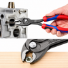 Knipex 8202200 TwinGrip Slip Joint Pliers gripping and removing a damaged screw from a wooden surface.