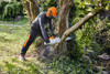 Professional user operating a STIHL MSA 300 18-inch cordless chainsaw while cutting a tree in a residential landscape setting.