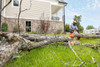 Contractor using a STIHL MSA 220 C 16-inch battery-powered chainsaw for storm cleanup and tree removal near a home.