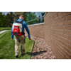 Operator using Milwaukee 3019-20PS M18 4-Gallon Backpack Sprayer with SWITCH TANK for perimeter pest control and herbicide application along a building foundation.