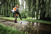 Operator using STIHL BA110115901 battery-powered backpack blower for quiet landscape maintenance in a park setting.