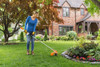 STIHL FSA 60 S cordless string trimmer trimming grass around flower beds and landscaping in a residential garden.