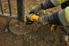 DeWalt DCG408B 20V MAX brushless angle grinder cutting a steel post with a metal cutting wheel on a construction site.