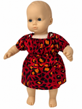 Front view Bright red animal print dress for 14–15 inch baby dolls featuring bold black and orange spots, short puff sleeves, gathered neckline, elastic waist, and flared skirt. Shown on a baby doll with blue eyes. Available from Doll Clothes Superstore.