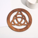 Basswood knotwork disc photographed at an angle to show wood grain and cutout detail