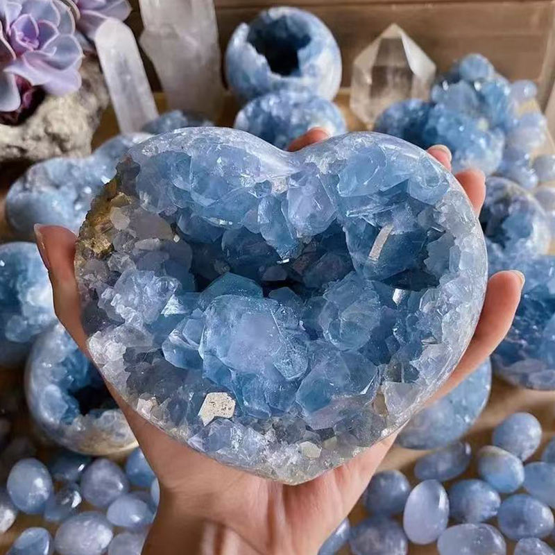 Blue celestite geode heart held in hand showing natural crystal structure