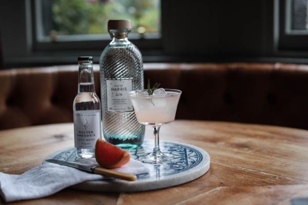 tonic eater alongsde bottle of alcohol on desk