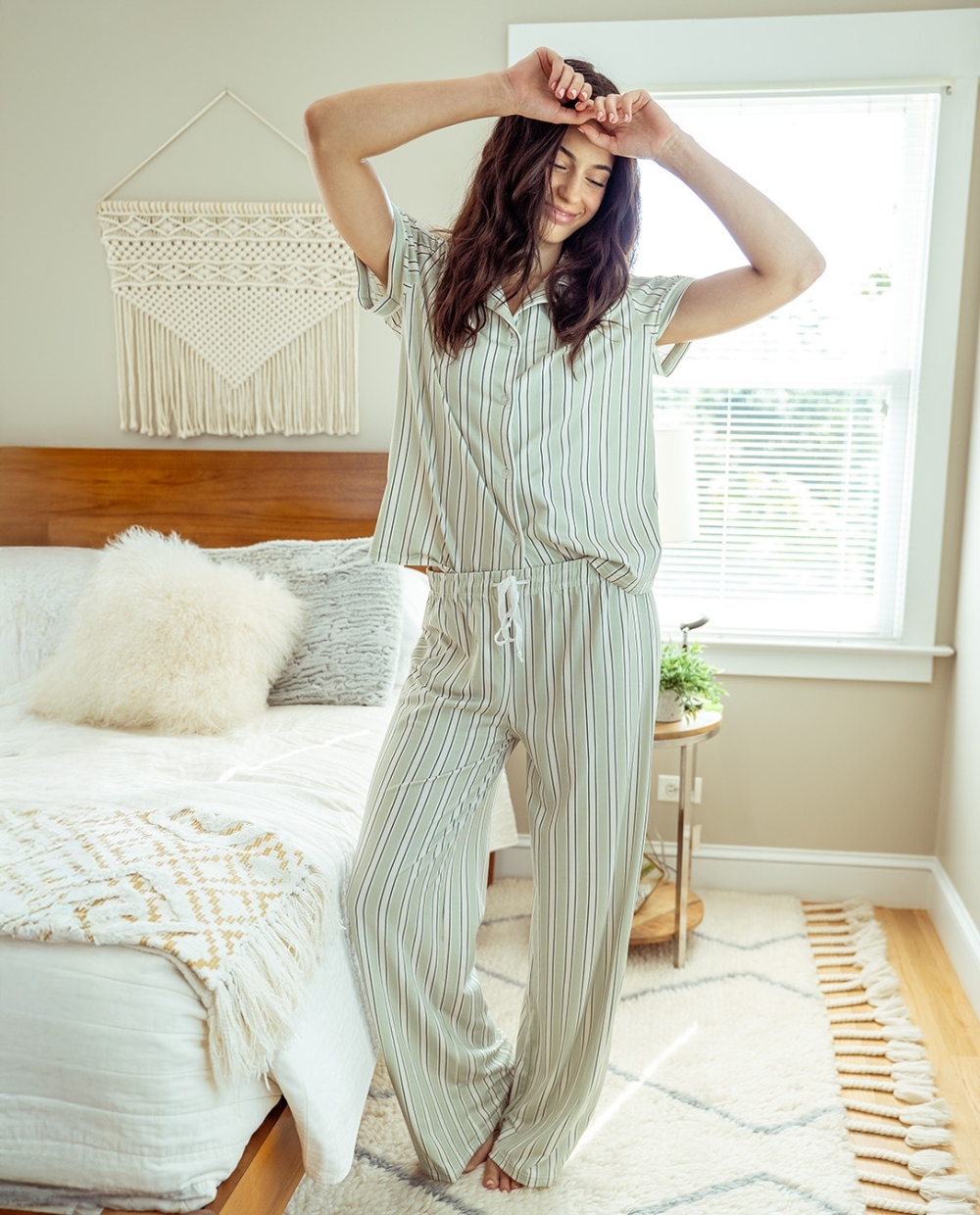 Woman smiling holding a cup of coffee in loungewear