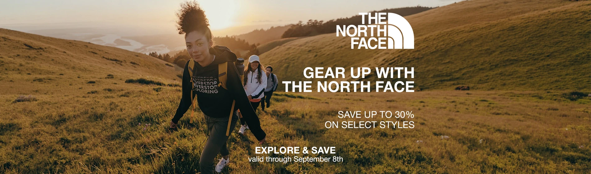 graphic, three hikers walking through tall golden grass on a rolling hillside at sunset, with the lead hiker wearing a black North Face hoodie and backpack, text, The North Face Limited-Time Sale: enjoy up to 30% off select models - valid through September 8th