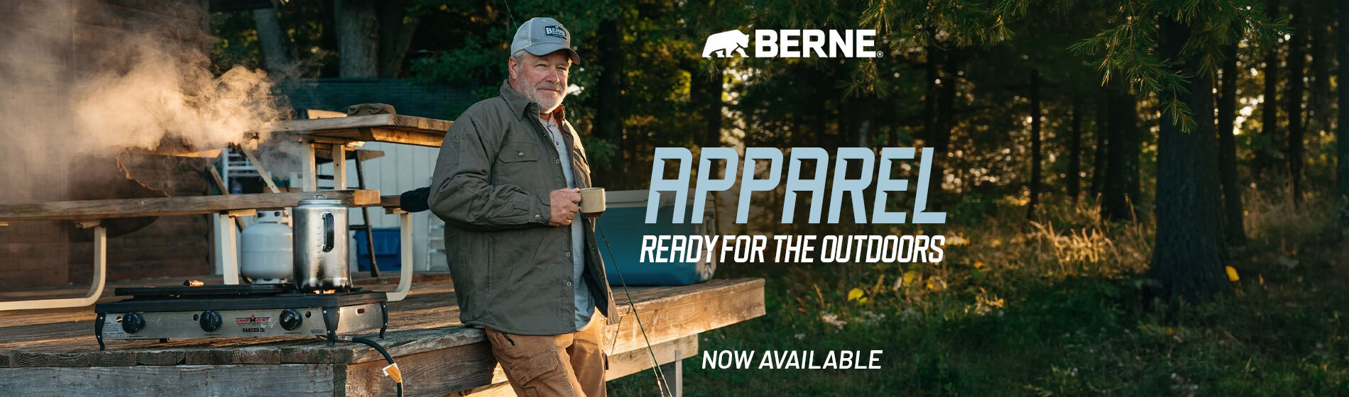 Graphic, a man wearing a cap and an olive green BERNE overshirt holding a mug, leaning against a wooden deck next to a steaming camp stove with a forest in the background, text,  Fresh Drop: BERNE APPAREL - Ready for the Outdoors!