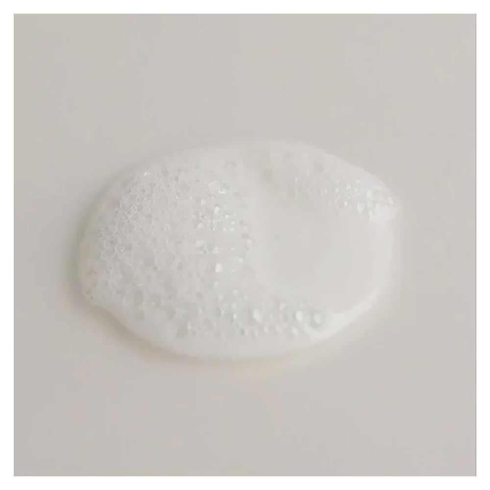 White creamy lather with clusters of tiny bubbles on a smooth, pale surface