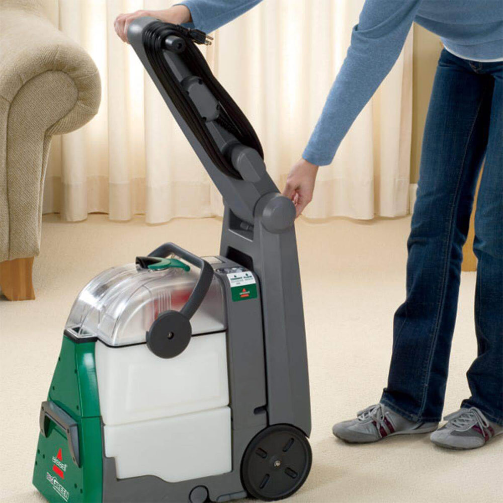 Person using Bissell Commercial Carpet Cleaner on indoor carpet surface