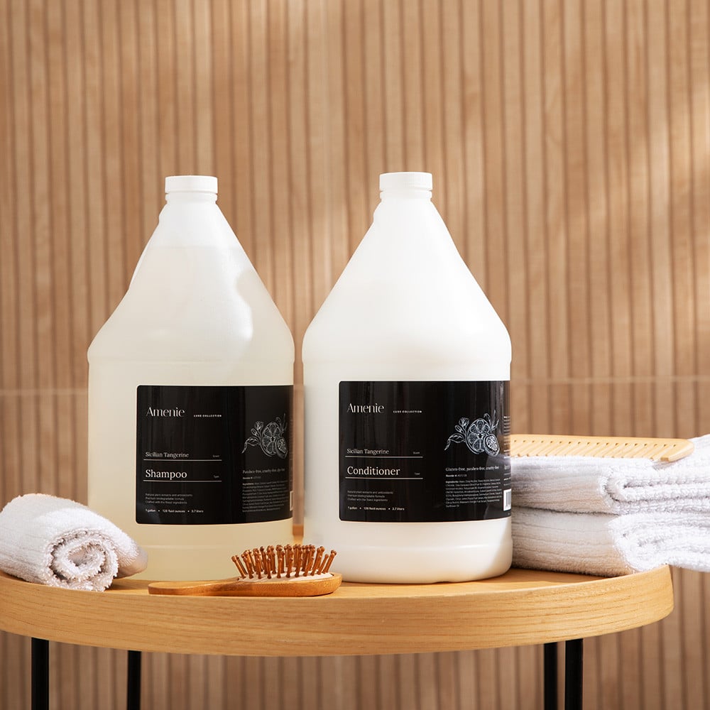 Amenie Sicilian Tangerine Shampoo and Conditioner gallon bottles on wooden spa tray display