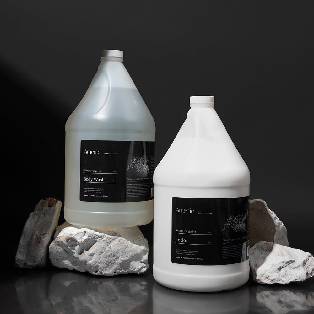 Amenie Sicilian Tangerine Shampoo, Conditioner, and Lotion gallon bottles on black stone background