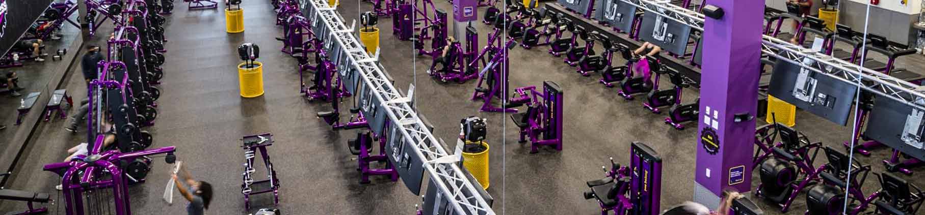 Inside of gym with rolled rubber flooring from Ecore and filled with ellipticals, weights, and lifting machines.