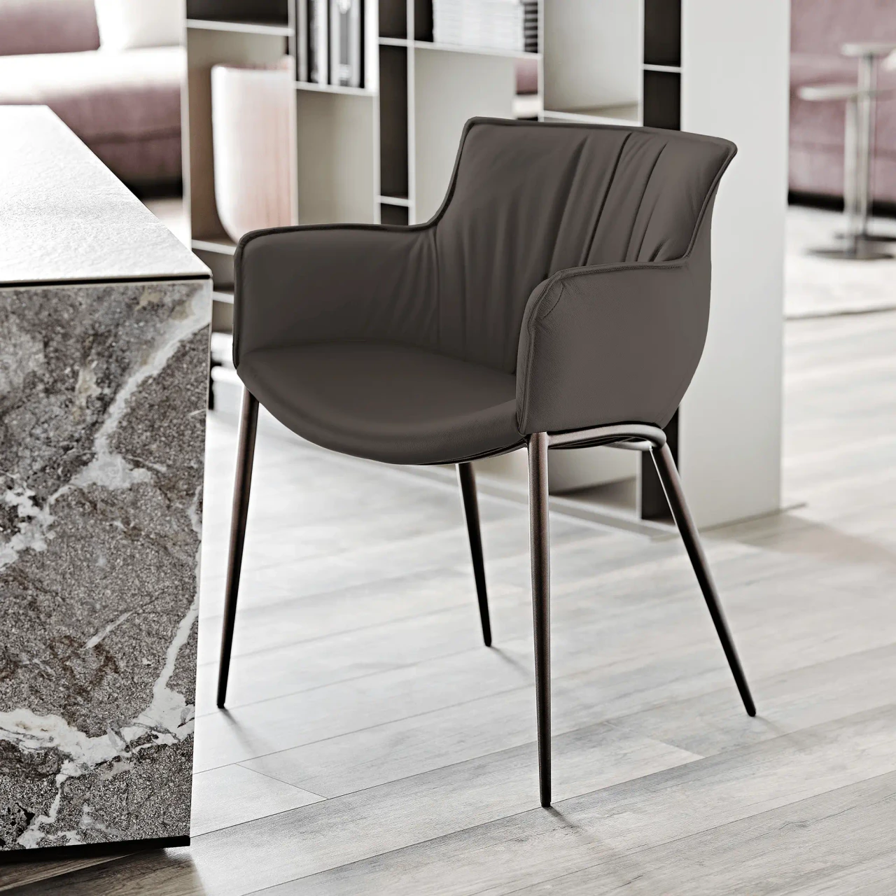 ARDESIA || BRONZE EMBOSSED STEEL - Modern dark brown faux leather armchair with slim metal legs, viewed from a three-quarter side angle.