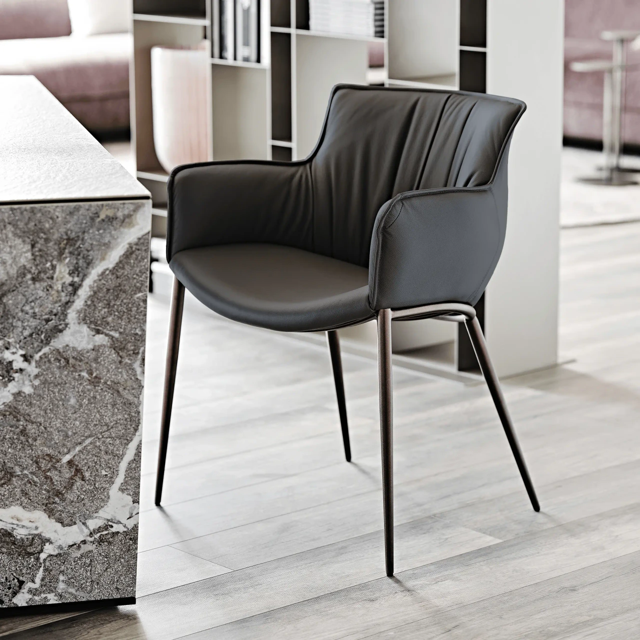 NERO || BRONZE EMBOSSED STEEL - Modern black leather accent chair with vertical stitching and slim metal legs, three-quarter side view.