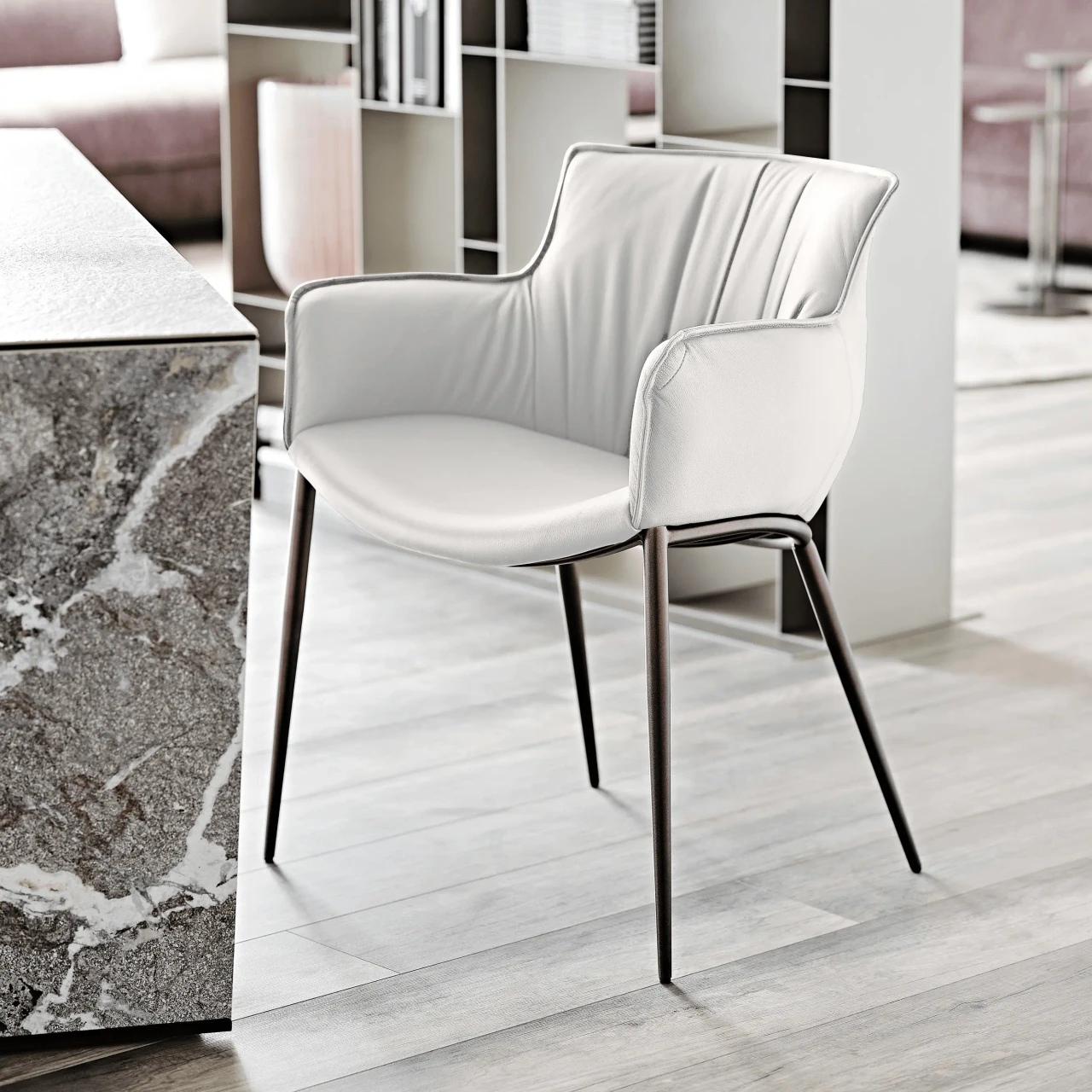 BIANCO || BRONZE EMBOSSED STEEL - Modern white leather armchair with slim dark metal legs, side view, featuring a curved back and integrated armrests.