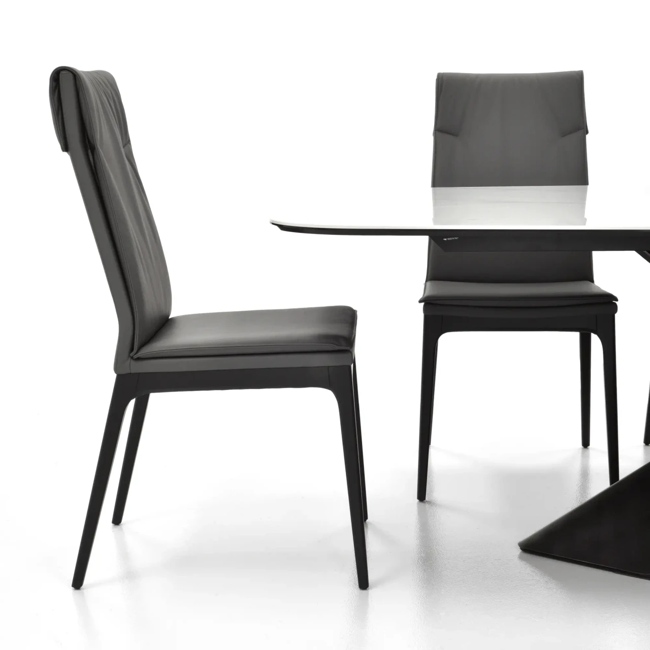 SMOKE - Cattelan Sofia Side Chair in smoke grey soft leather with matt black beech legs, side view in a dining room setting.