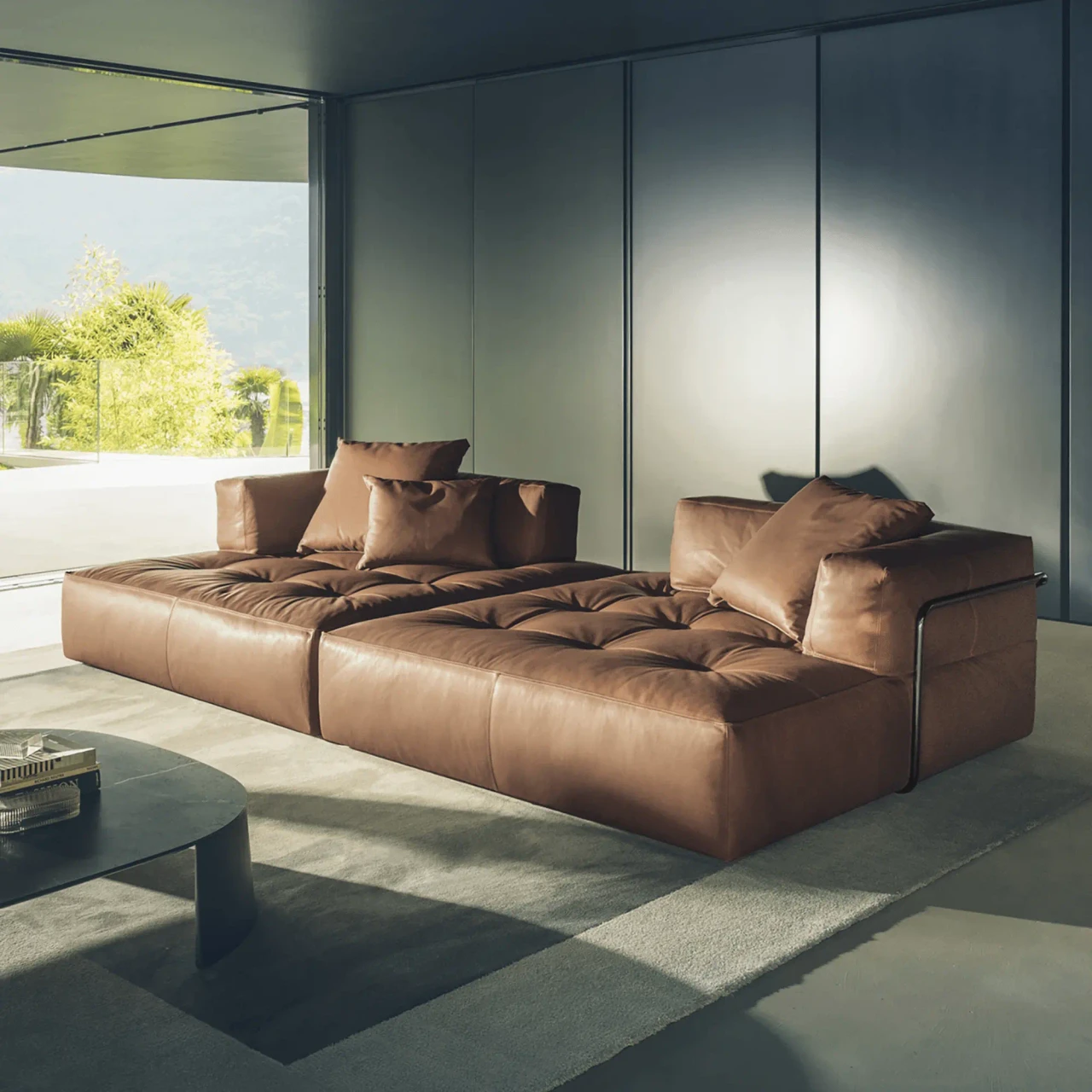 Brown leather modular sectional sofa with tufted seats and metal frame, modern style, three-quarter view.