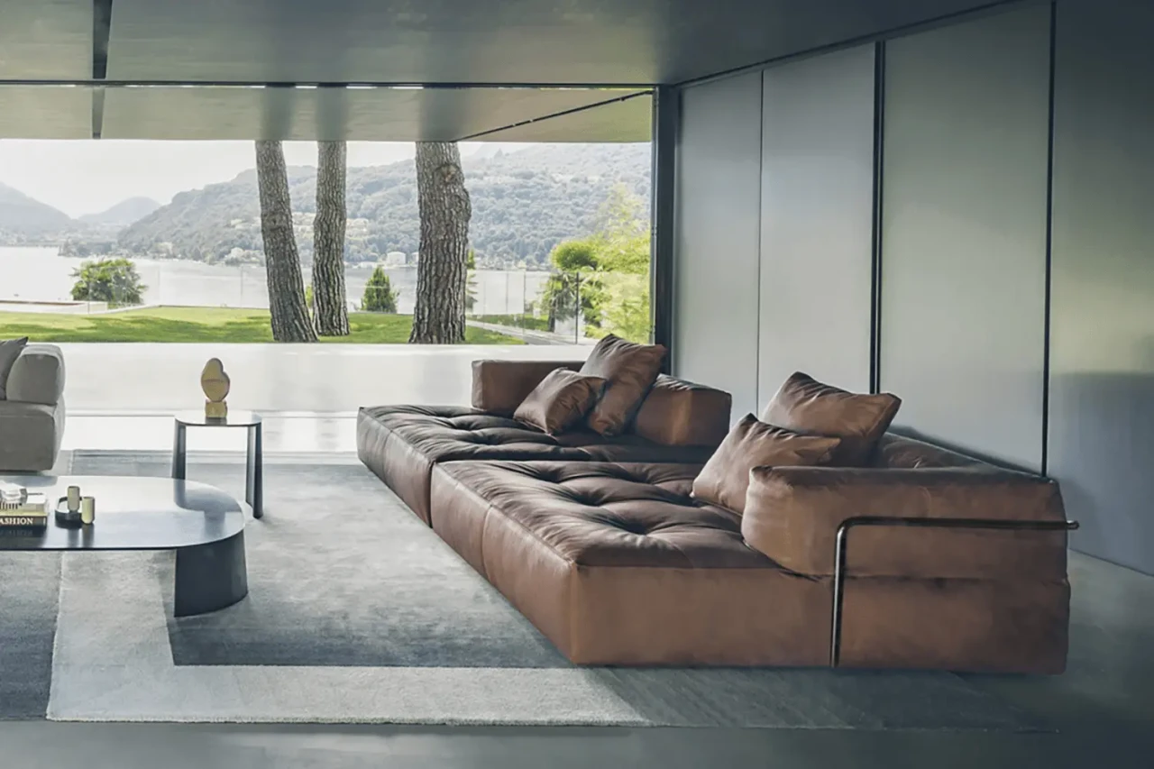 Brown leather modern modular sectional sofa with tufted cushions, viewed from a side angle in a minimalist living room.