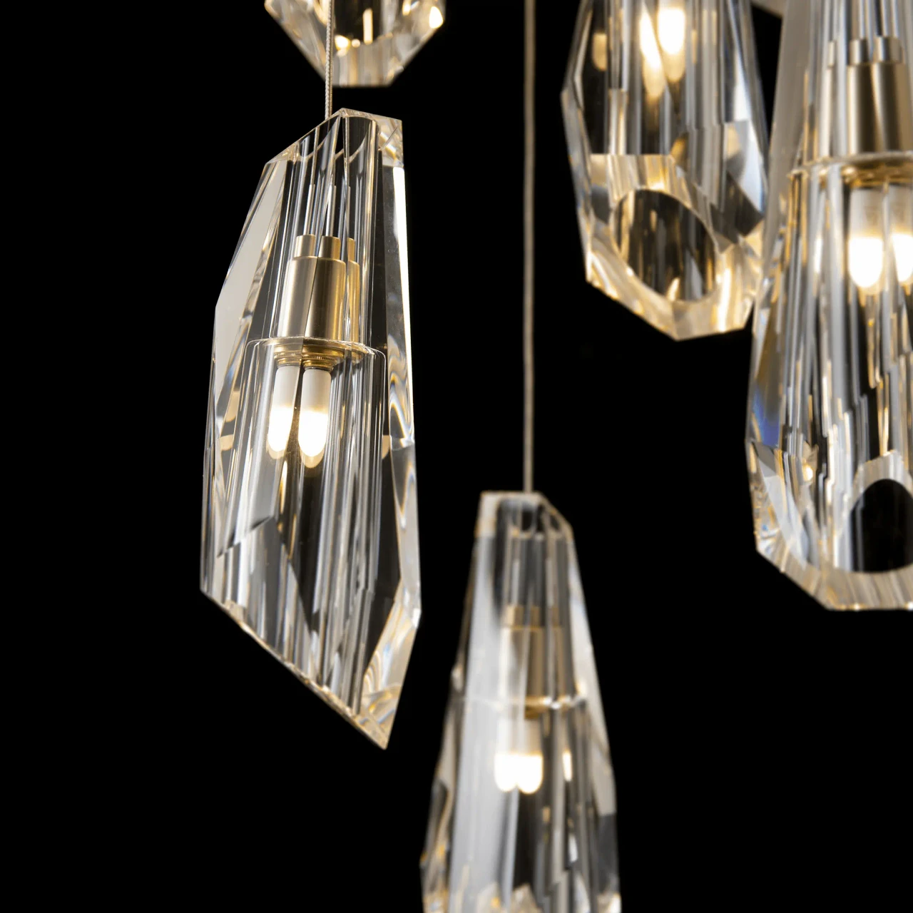 Closeup - Close-up of Luma 9-light Chandelier, modern brass finish and crystal, featuring faceted pendants, angled view.