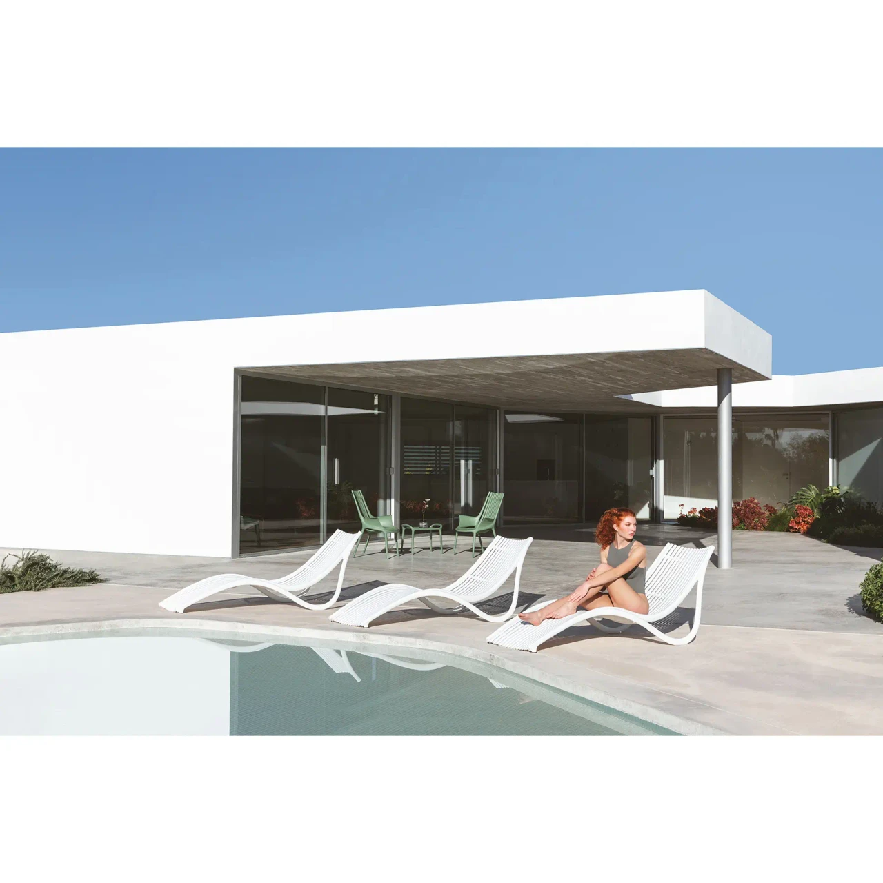 Vondom Ibiza Sun Lounger, modern ecru polypropylene outdoor lounge chairs by a pool, side view lifestyle shot.