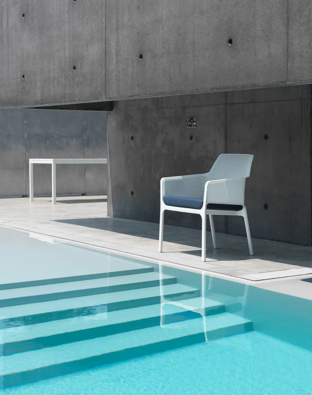 Nardi Net Relax outdoor lounge chair, white polypropylene with grigio Sunbrella cushion, side view by poolside.