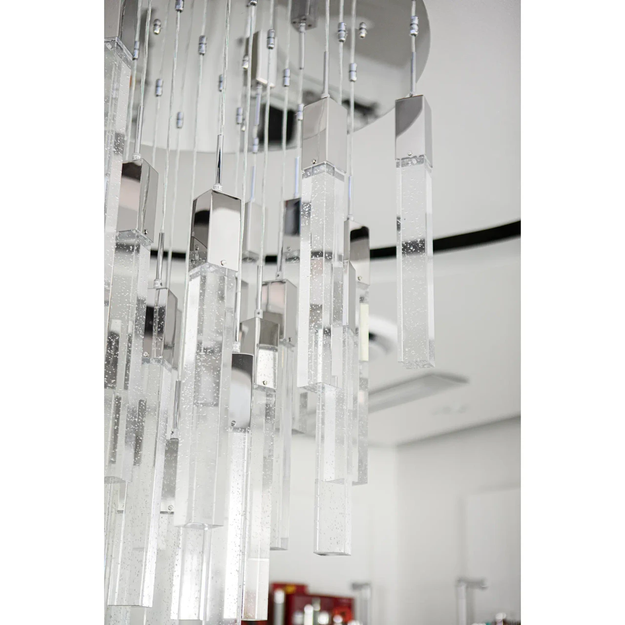 25 - Close-up of Glacier Suspension Fixture in polished chrome and bubbled glass, modern style, hanging in a white room.