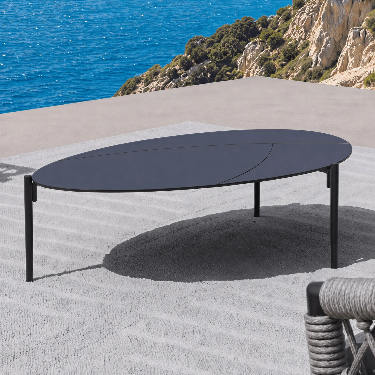 Laguna Cocktail Table, modern oval charcoal aluminum powdercoat coffee table, outdoor patio setting, angled side view.
