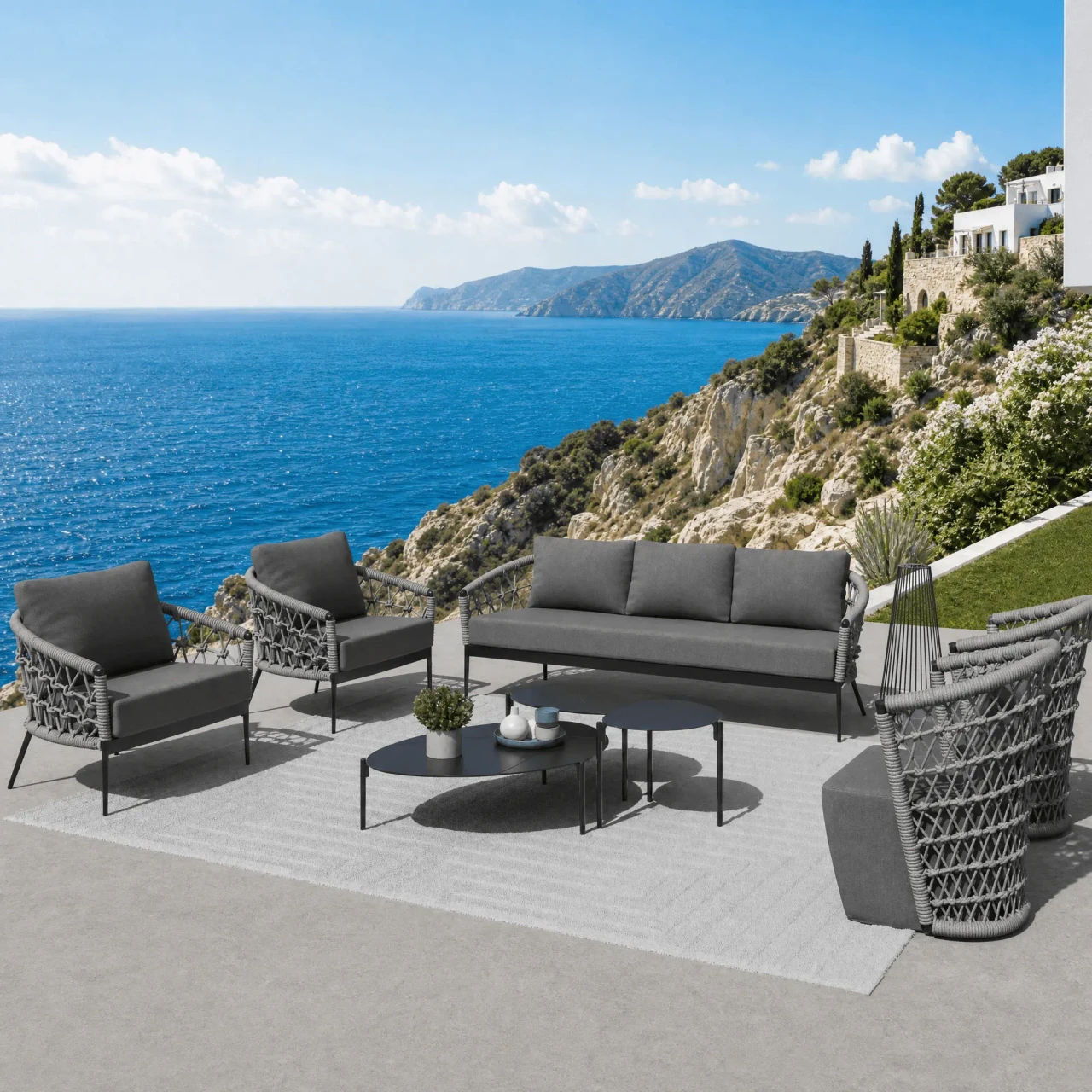 Charcoal aluminum powdercoat Laguna Cocktail Table with matching outdoor sofa and chairs on a patio overlooking the ocean.