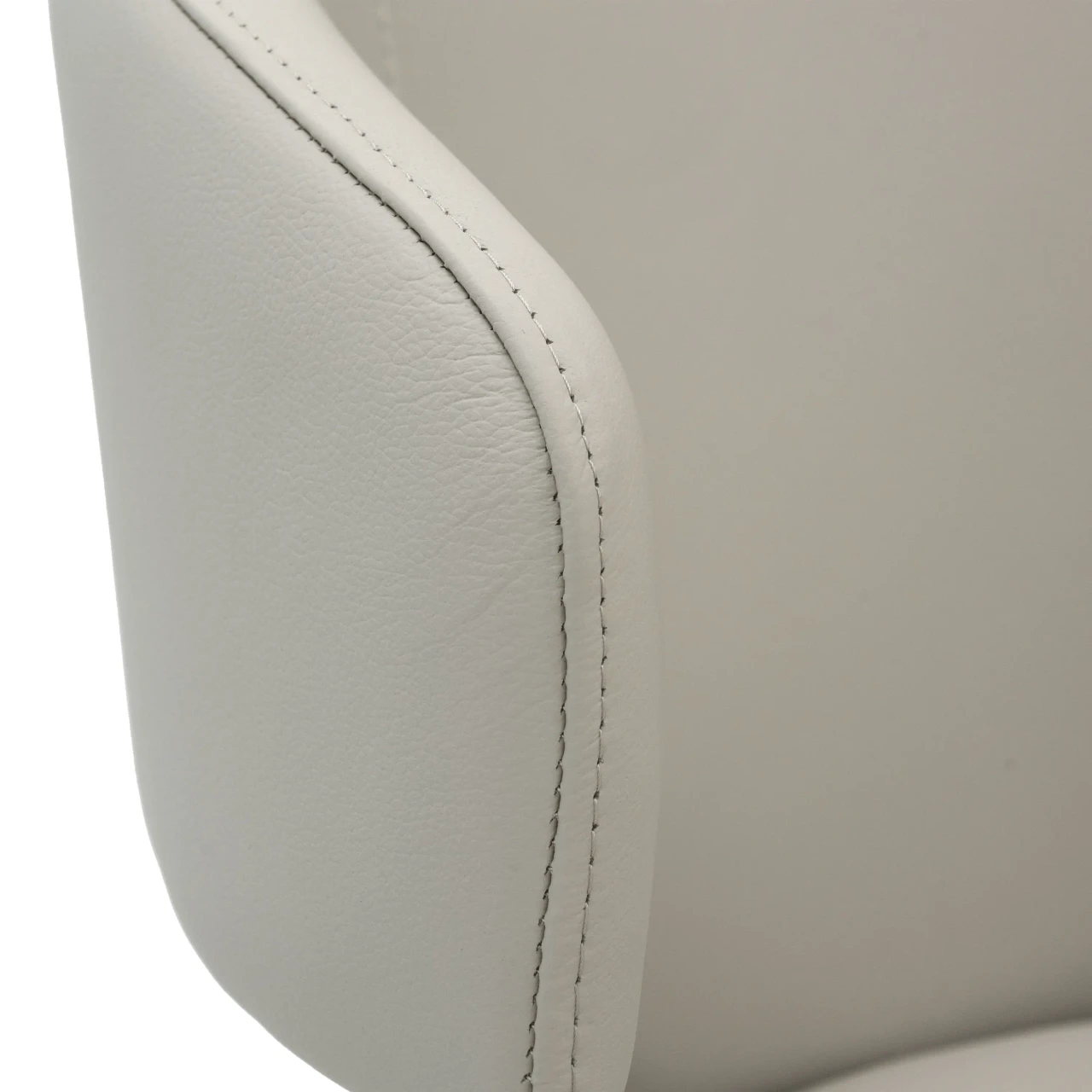 BEIGE || Closeup - Close-up side view of a white leather modern chair featuring detailed topstitching along the curved edge.