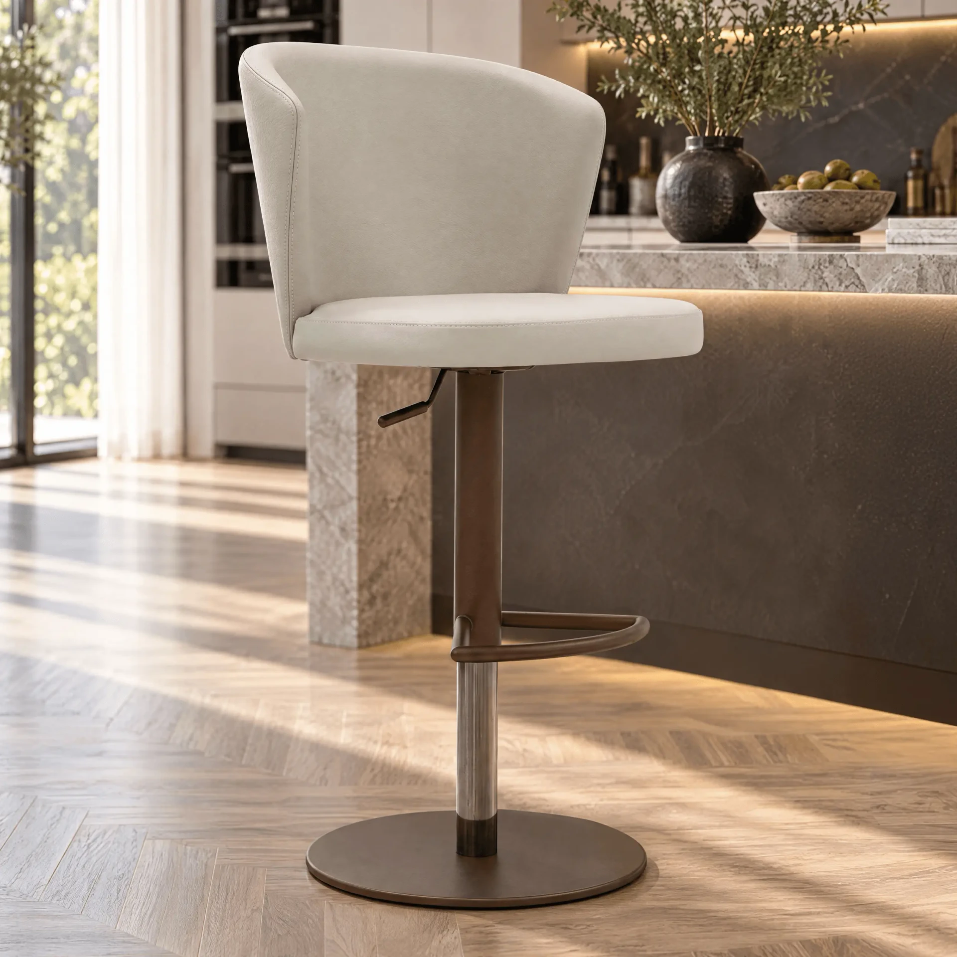 Tess Bar Stool in beige leather with bronze base, post, and footrest, side view in a modern kitchen setting.