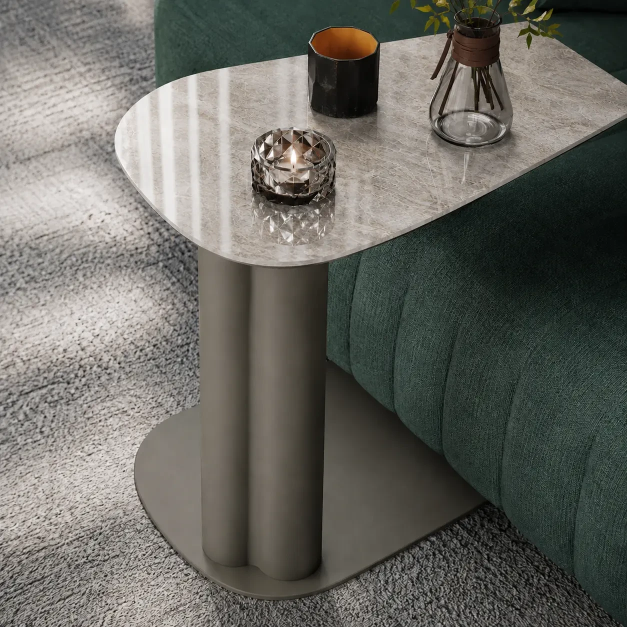 A - Modern side table with grey marble top and matte grey metal pedestal base, angled view next to a green sofa.