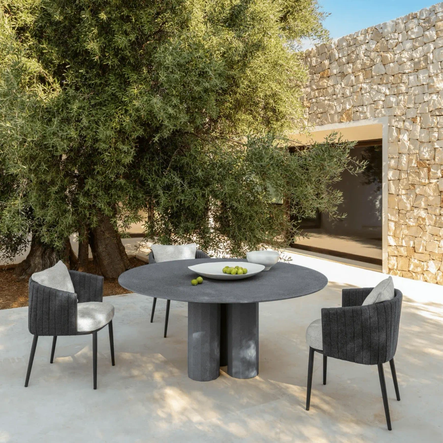 Talenti SRL Salinas Round Dining Table in Concrete Grey Cement with chairs, outdoor patio setting, eye-level wide shot.