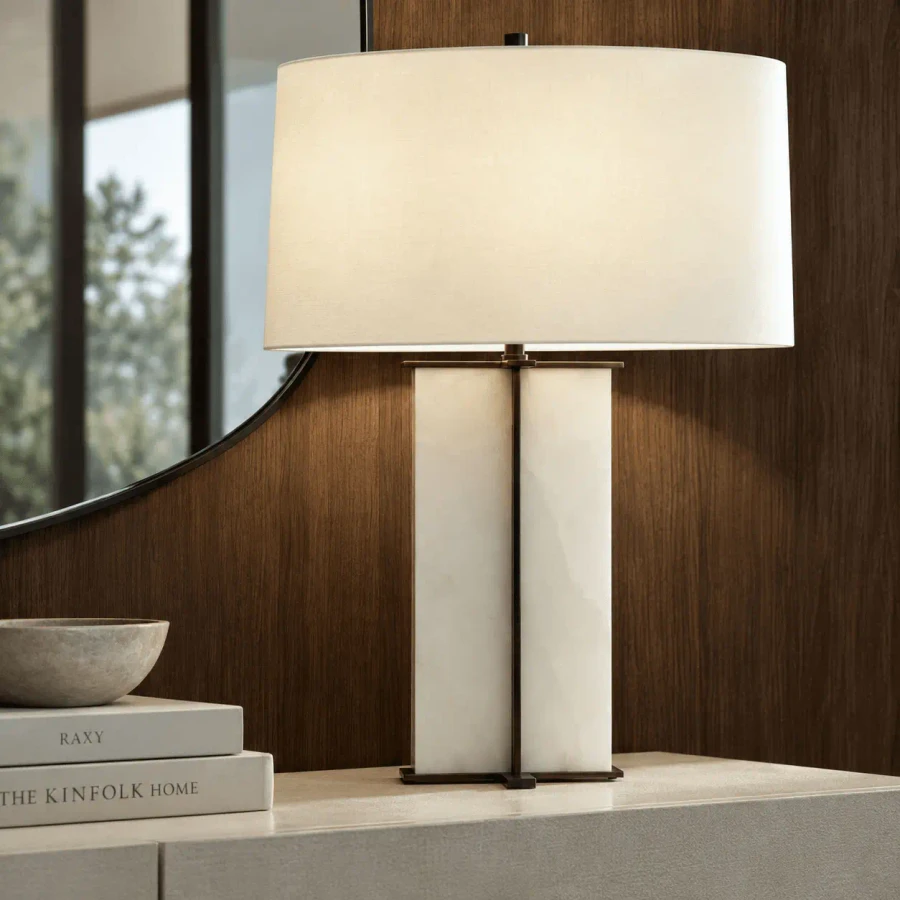 Lyon Table Lamp, modern bronze metal and alabaster with white linen shade, front view in a living room setting.