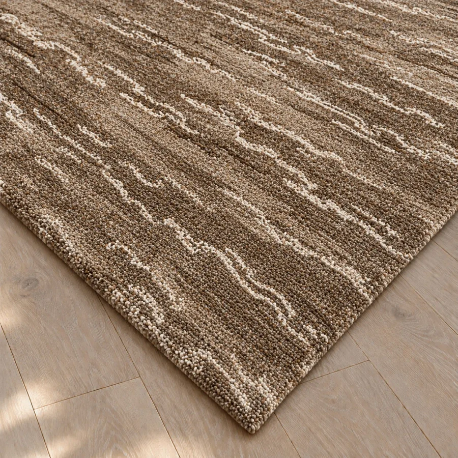 Close-up angle of Untamed Area Rug in Sage/Fog, hand knotted 100% wool with brown and cream textured stripes on wood floor.
