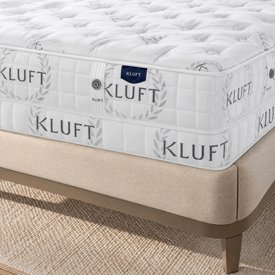 QUEEN - Kluft Baron X-firm Mattress, white quilted fabric, extra firm, bedroom setting, close-up side angle on beige bed frame.