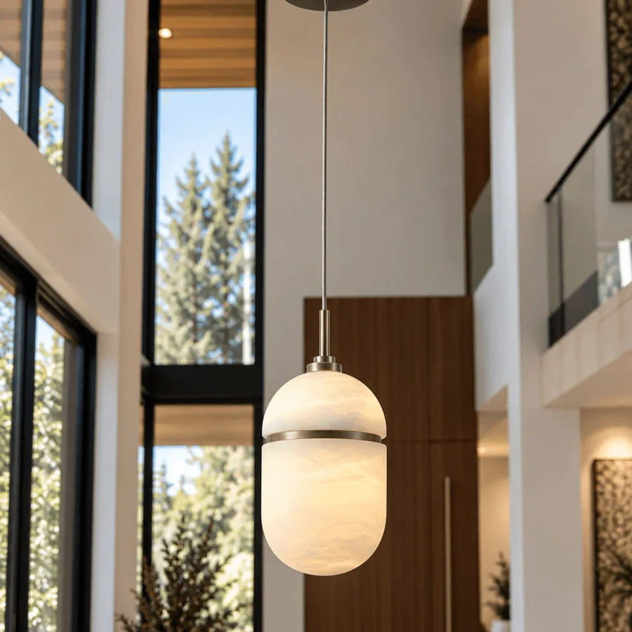 Sedona Oval Pendant in Aged Brass with Alabaster Globe, modern style, eye-level view in a high-ceiling living room.