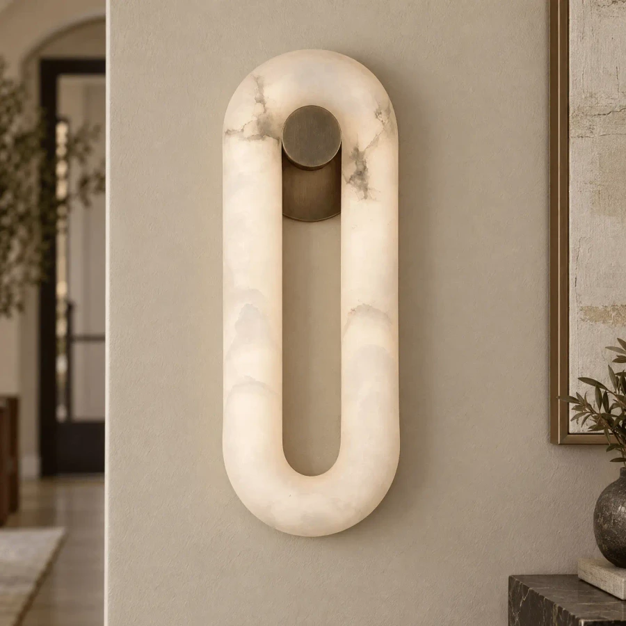 SMALL - Sedona Sconce, modern oval wall light in Aged Brass and Alabaster, integrated LED, front view in a living room setting.
