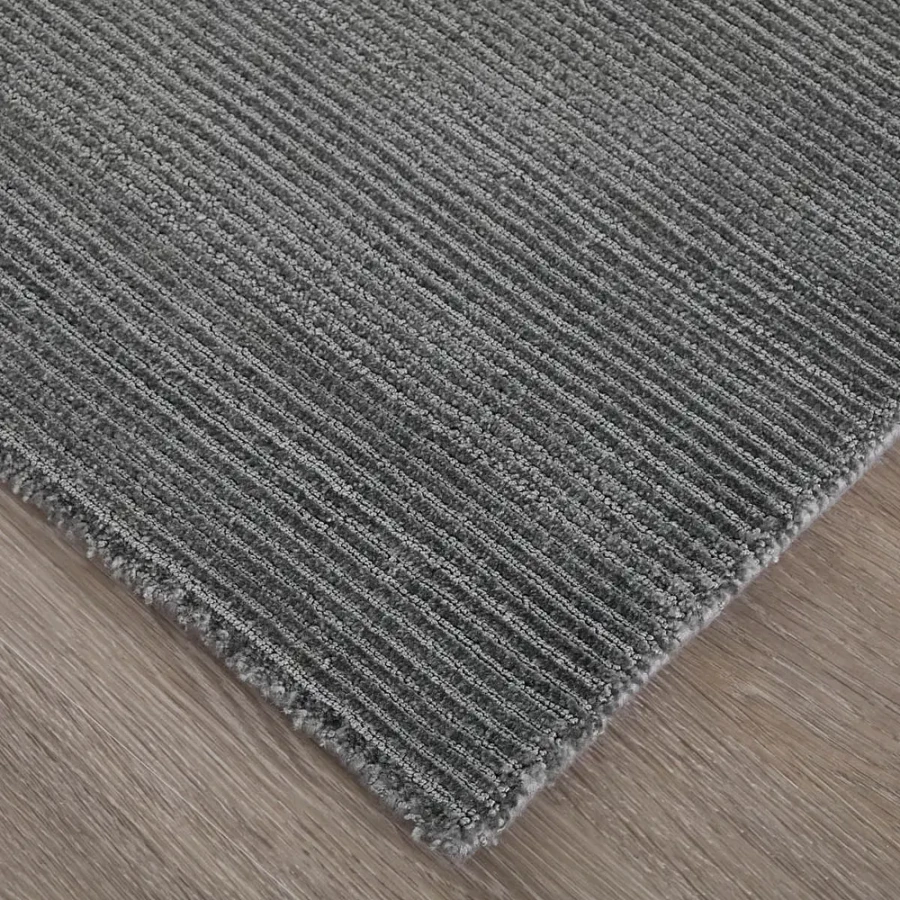 Feizy Abbott Area Rug in grey, 100% nylon hand woven with ribbed texture, close-up angle on wood floor.