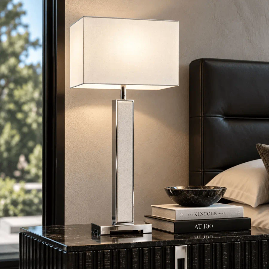 Malerba One And Only Tall Table Lamp, modern stainless steel with white shade, side view in bedroom setting.