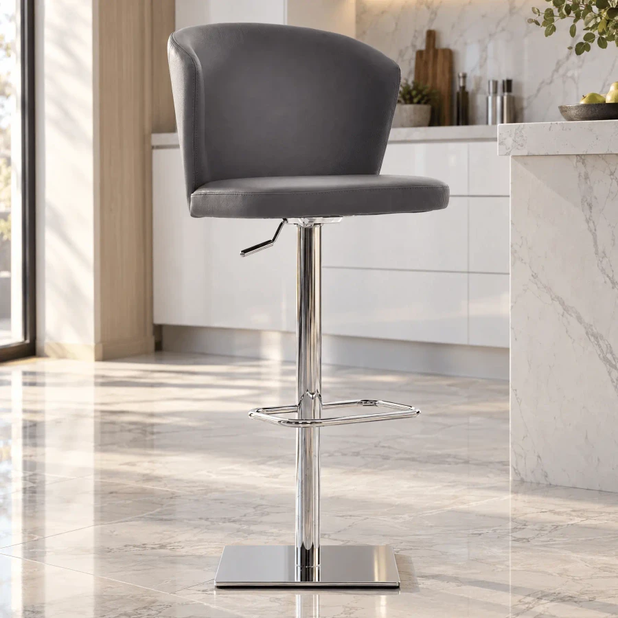 GREY LEATHER - Tess Bar Stool in grey leather with chrome base, post, footrest and lift, side view in a modern kitchen setting.