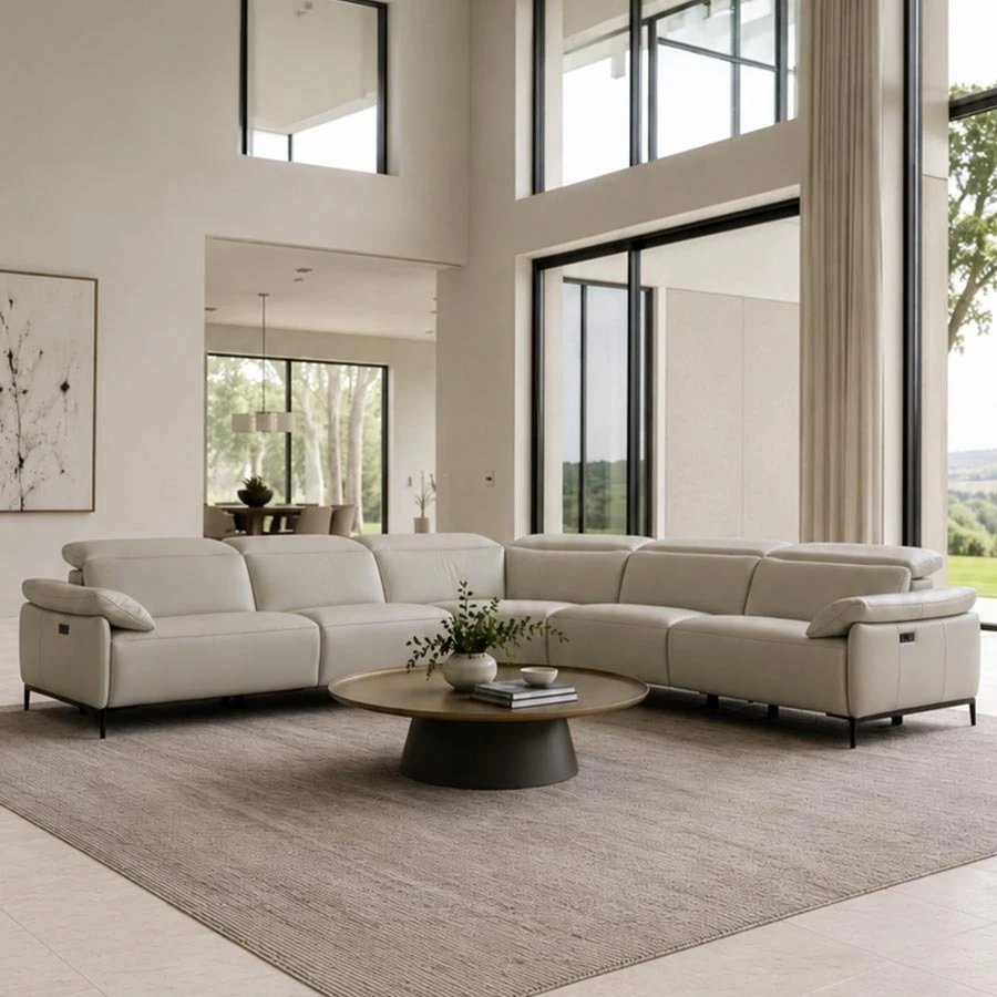 Off-white leather sectional sofa with reclining headrests paired with a round brass round coffee table