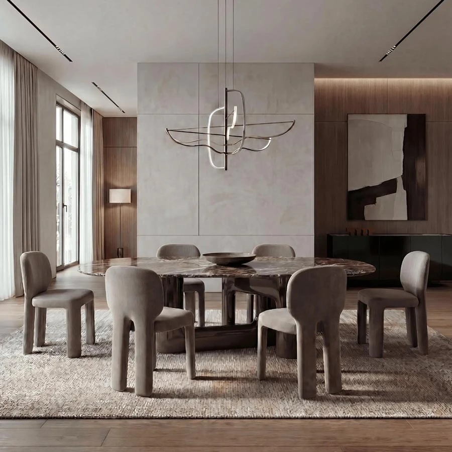 Oval dark marble dining table surrounded by light grey upholstered dining chairs with rounded legs