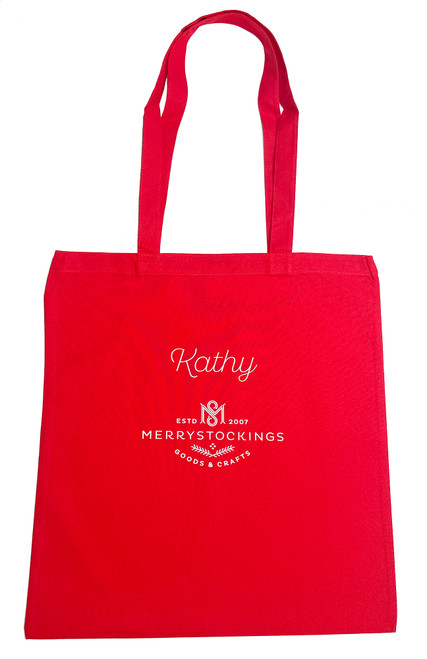 Red MerryStockings tote bag personalized with your name personalized on the bag, featuring white printed logo and text